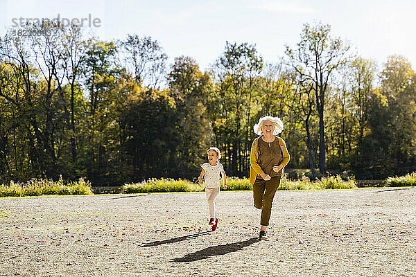 Verspielte Seniorin läuft mit Enkelin im Park