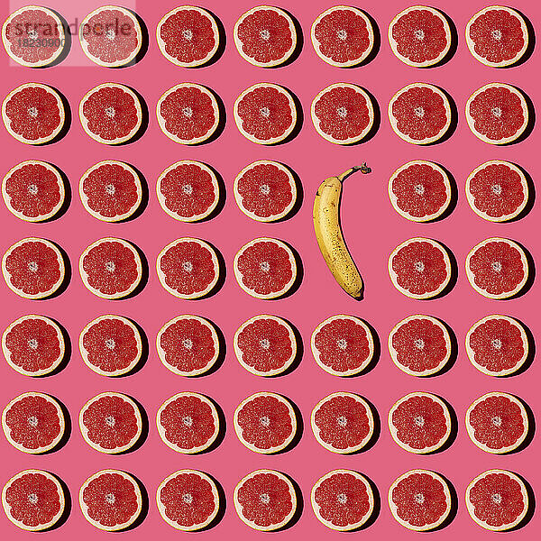 Muster aus halbierten Grapefruits mit einer einzelnen Banane in der Mitte