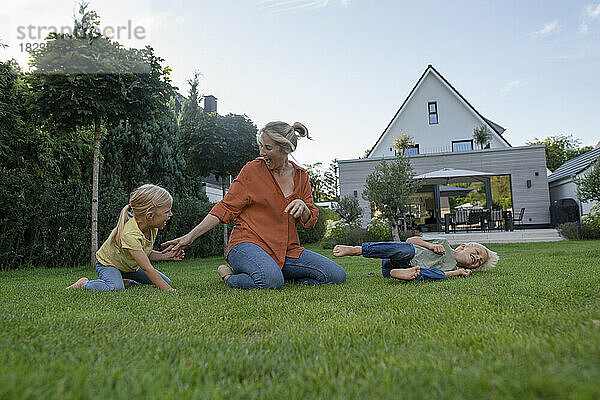 Fröhliche Mutter mit Kindern  die im Garten spielen