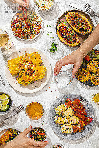 Der Tisch ist mit verschiedenen Gerichten gefüllt  darunter Chop Suey  gefüllte Kartoffeln  Fajitas  Reismuffins  Ricotta-Brötchen und verschiedene Salate