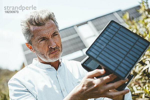 Mann untersucht Solarpanel-Ausrüstung an einem sonnigen Tag