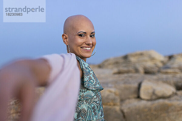 Glückliche Frau mit Alopezie genießt den Sonnenuntergang