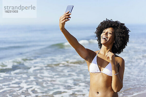 Glückliche junge Frau  die an einem sonnigen Tag ein Selfie mit dem Smartphone macht
