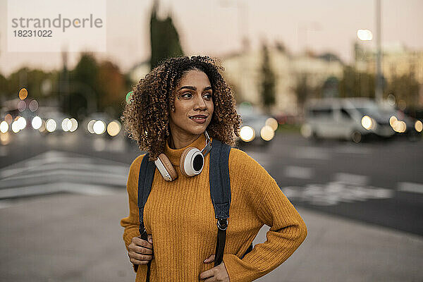 Schöne junge Frau mit Rucksack und kabellosen Kopfhörern