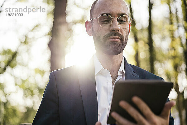 Businessman holding tablet PC on sunny day
