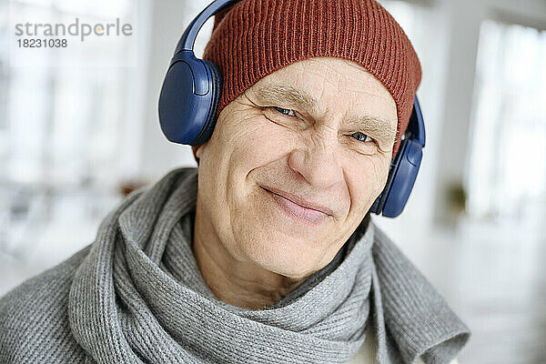 Glücklicher Mann mit Strickmütze  der über Kopfhörer Musik hört