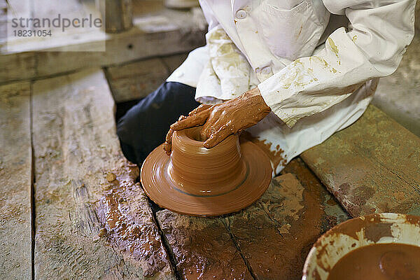 Craftsman molding clay on pottery wheel in factory