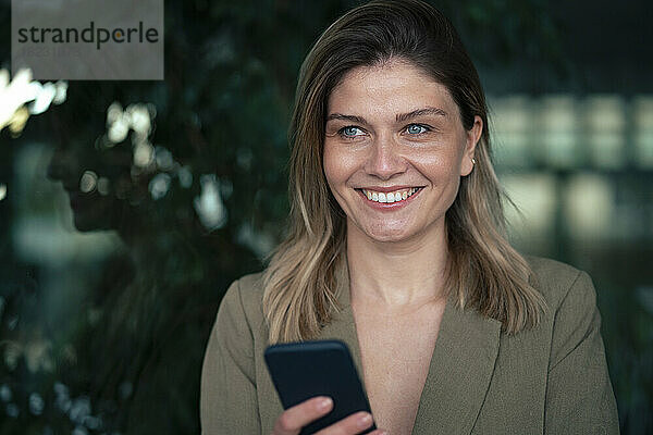 Lächelnde blonde Geschäftsfrau mit Smartphone