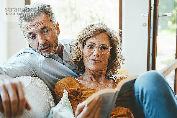 Reife Frau und Mann lesen zu Hause gemeinsam ein Buch