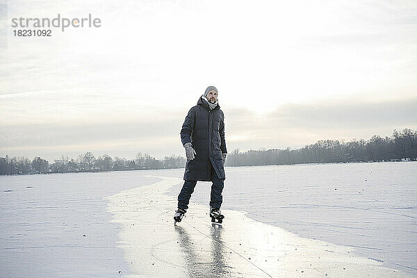 Mann Schlittschuhlaufen auf zugefrorenem See im Winter