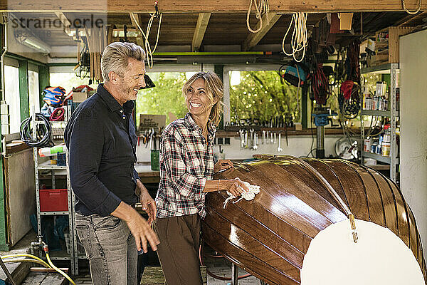 Glücklicher Mann und Frau polieren Boot in der Garage