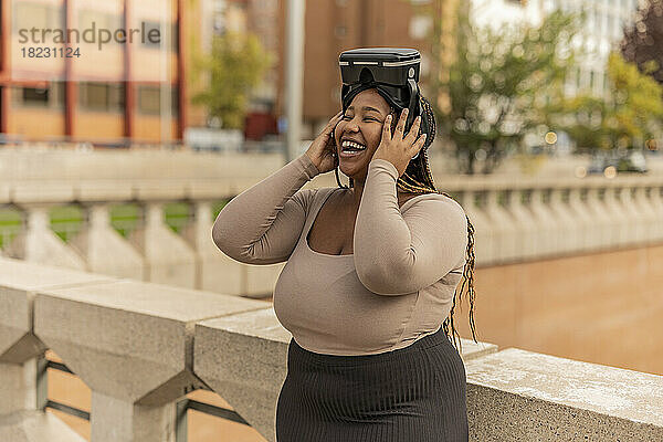 Frau lacht mit Virtual-Reality-Simulator am Geländer