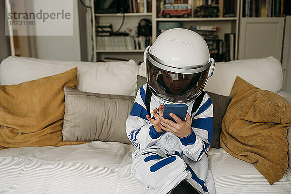 Girl wearing space costume using smart phone on sofa in living room