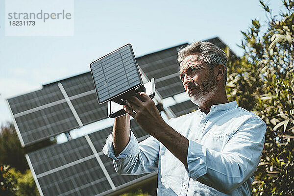 Reifer Mann untersucht Solarpanel-Ausrüstung an einem sonnigen Tag