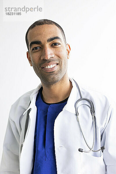 Smiling doctor with stethoscope against white background