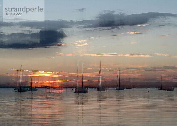 Germany  Baden-Wurttemberg  Allensbach  Sailboats moored in harbor on shore of Lake Constance at sunset