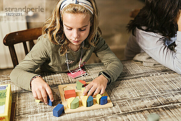 Girl playing with toy blocks at table in home