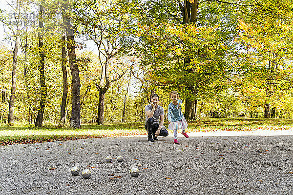 Mädchen spielt Boule mit Vater im Park