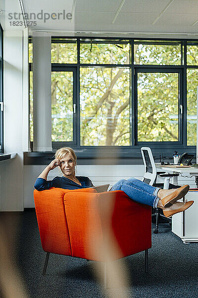 Businesswoman sitting on armchair at workplace