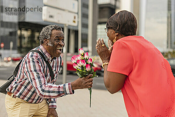 Älterer Mann überrascht Frau mit Blumenstrauß