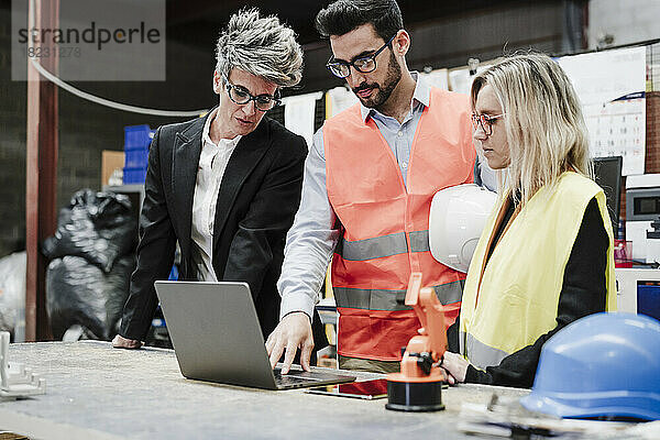 Ingenieur mit Kollegen diskutieren über Laptop in der Industrie