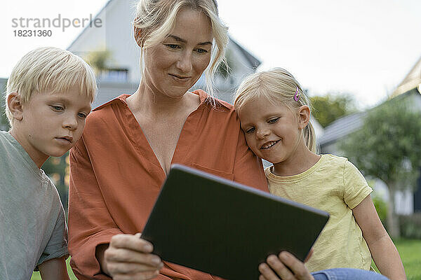 Lächelnde Frau zeigt Kindern Tablet-PC