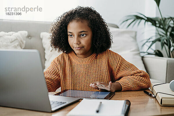Mädchen macht zu Hause Hausaufgaben auf Laptop und Tablet-PC