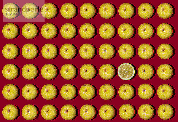 Muster aus halbierten Zitronen  flach auf rotem Hintergrund ausgelegt  wobei eine einzelne auf dem Kopf liegt
