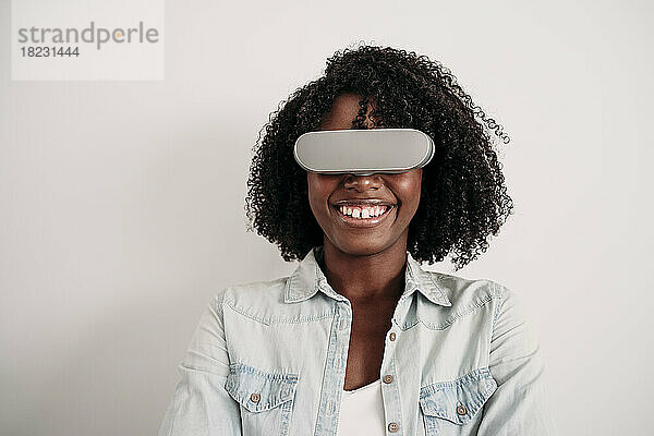 Glückliche junge Frau mit lockigem Haar und Virtual-Reality-Headset
