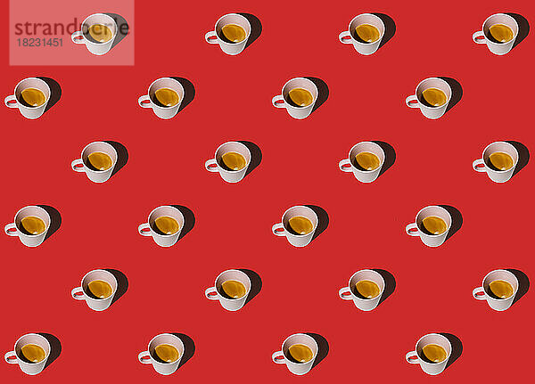 Muster aus in Reihen stehenden Tassen Kaffee vor rotem Hintergrund