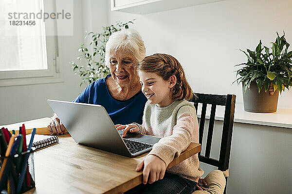 Großmutter hilft Enkelin beim E-Learning per Laptop zu Hause