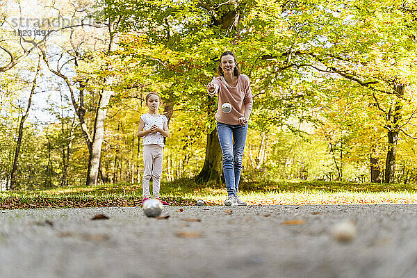 Glückliche Mutter mit Tochter  die im Park Boule spielt