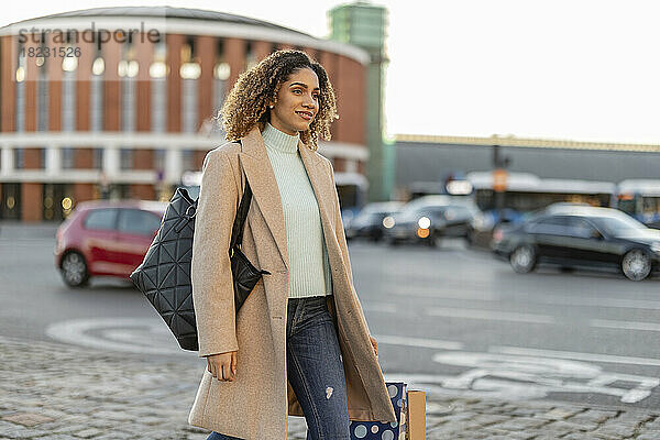Junge Frau mit Einkaufstasche geht auf Fußweg