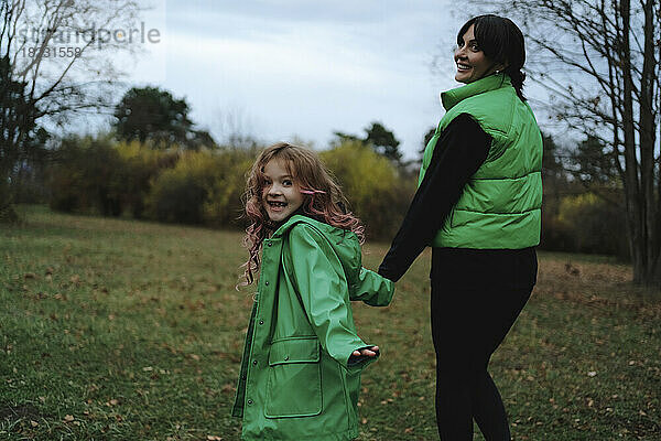Glückliches Mädchen Händchen haltend mit Mutter  die im Park spaziert