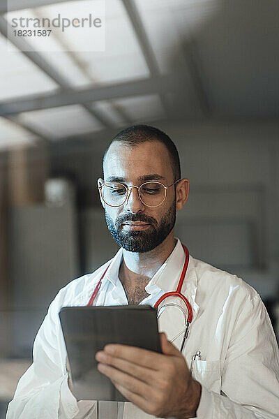 Doctor using tablet PC in hospital seen through glass