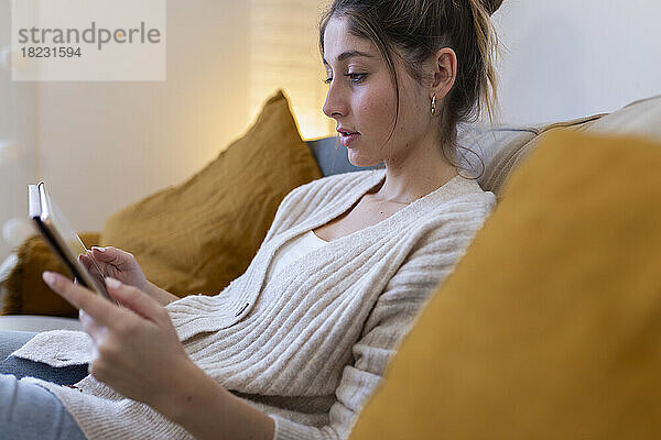 Smiling woman using tablet PC on sofa at home