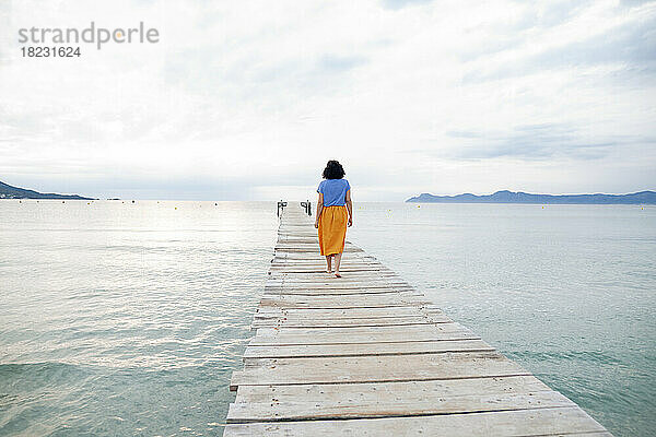 Woman walking on jetty amidst sea