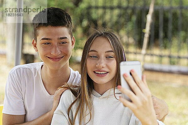 Teenage girl taking selfie with boy outdoors
