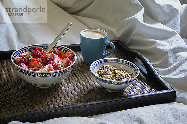 Tablett mit einer Tasse Kaffee  Müsli und Joghurt mit Erdbeeren
