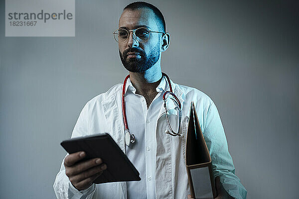 Arzt hält Tablet-PC vor Wand