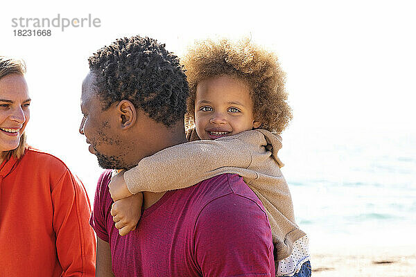 Lächelndes Mädchen genießt es mit seinen Eltern am Strand