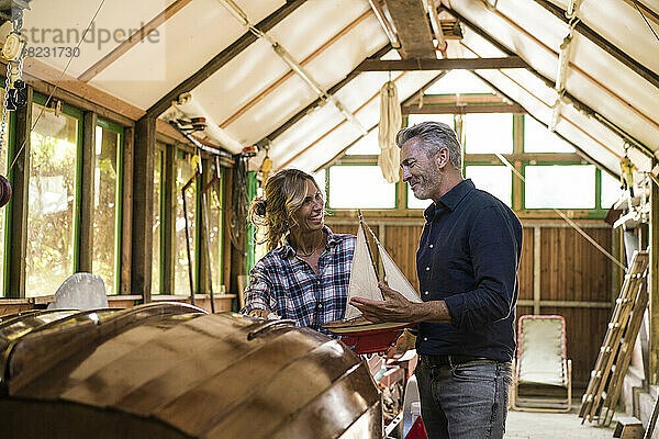 Glücklicher Mann und Frau diskutieren in der Garage über ein Segelbootmodell