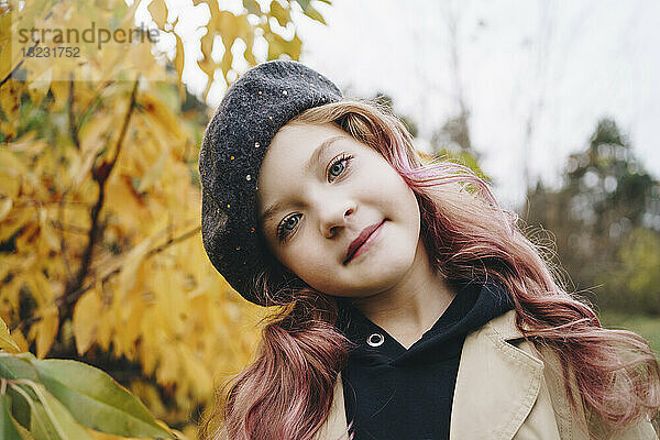 Lächelndes süßes Mädchen  das im Herbstpark steht