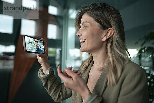 Glückliche Geschäftsfrau bei Videoanruf mit Kollege über Smartphone