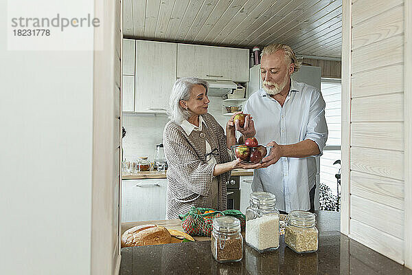 Älteres Paar hält frische Äpfel in der Küche