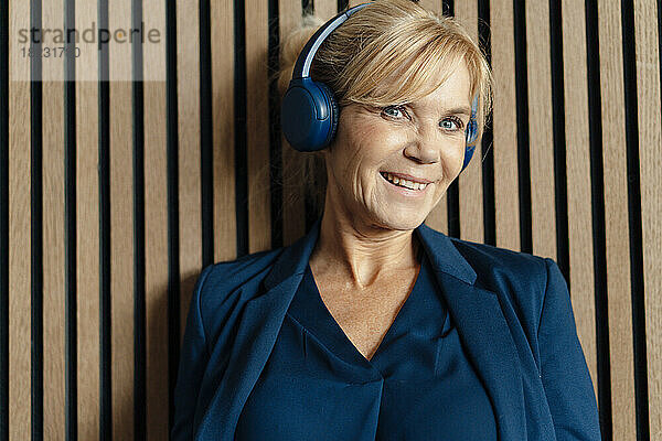 Glückliche Geschäftsfrau  die über kabellose Kopfhörer Musik hört