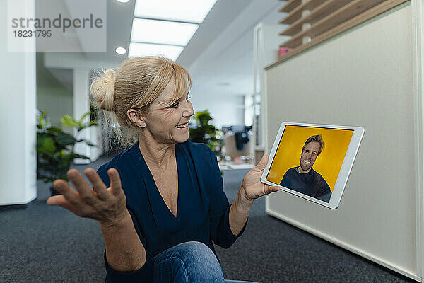 Lächelnde Geschäftsfrau führt Videoanruf über Tablet-PC im Büro