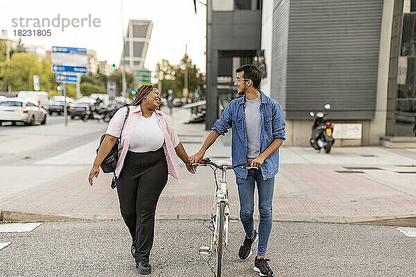 Glückliche Frau und Mann  die mit dem Fahrrad auf der Straße unterwegs sind