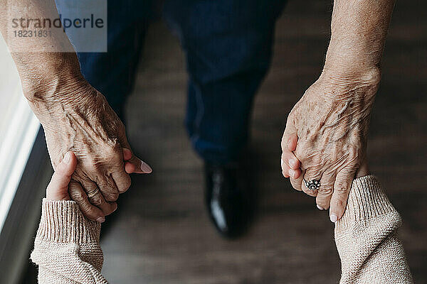 Ältere Frau hält zu Hause die Hände ihrer Enkelin