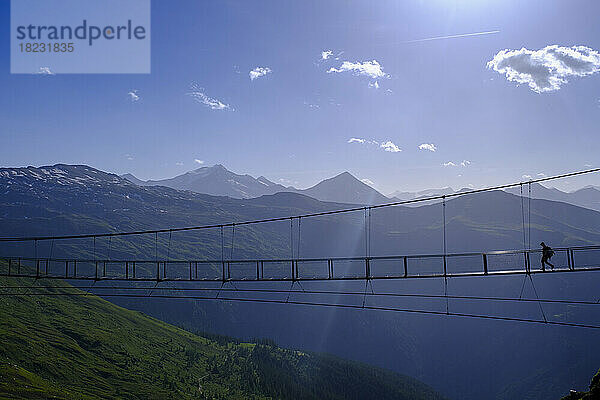 Österreich  Salzburg  Bad Gastein  Silhouette einer Person  die eine Hängebrücke über das Gasteinertal überquert